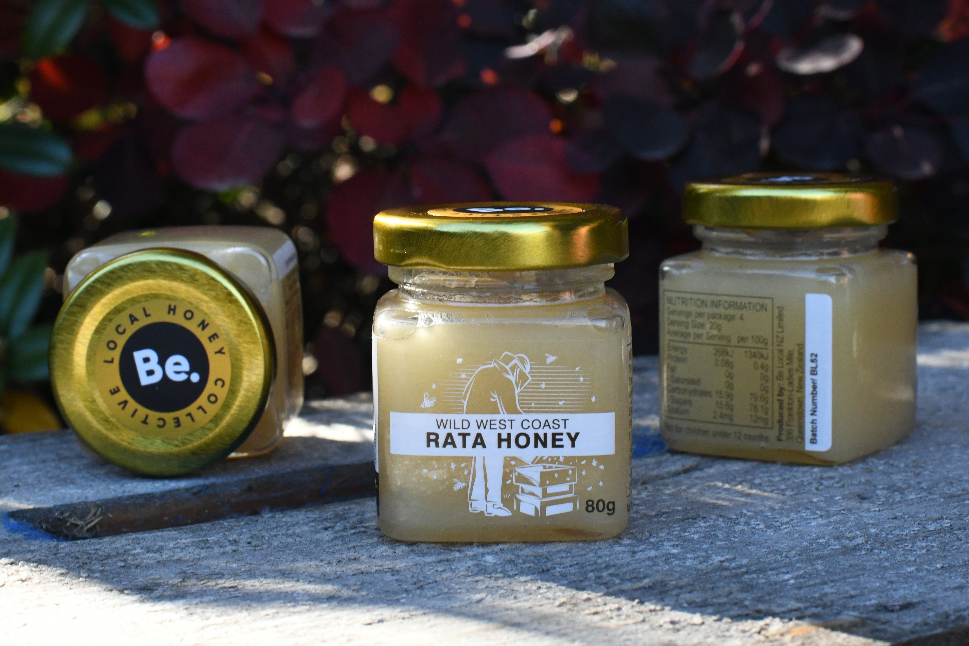 Three jars of honey on a honey box with a blurred natural background